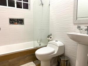 a white bathroom with a toilet and a sink at Casa con Parqueo Privado, Patio y Jacuzzi. in Santo Domingo