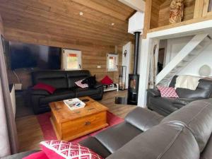 a living room with leather furniture and a wooden ceiling at Chalet La Plagne Montalbert Pied des Pistes in Aime-La Plagne