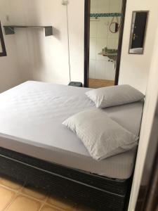 łóżko z białą pościelą i lustrem w pokoju w obiekcie Pousada&Hostel Lincoln Praia Grande w mieście Praia Grande