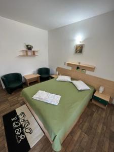 a bedroom with a green bed in a room with chairs at Motel Select in Satu Mare