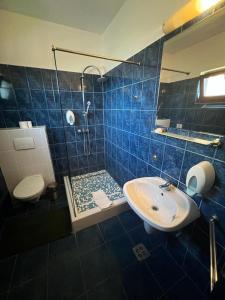 uma casa de banho em azulejos azuis com um chuveiro e um lavatório. em Motel Select em Satu Mare