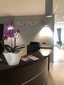 a reception desk with a vase with purple flowers on it at Aqua Hotel in Polkowice