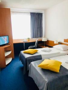um quarto de hotel com duas camas com almofadas amarelas em Aqua Hotel em Polkowice