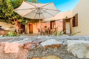 een patio met een parasol en een tafel en stoelen bij Nikolas House in Xirokámbion