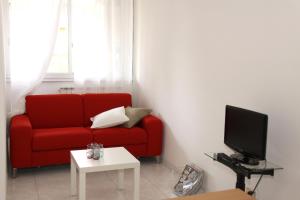 a living room with a red couch and a tv at Terrazze Fiorite in Bergamo
