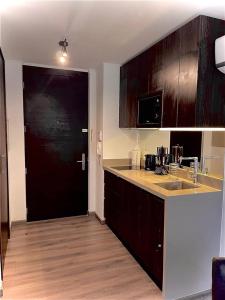 a kitchen with wooden cabinets and a black door at Apart Hotel in downtown Santiago Historic Center in Santiago