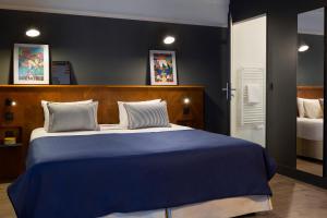 a bedroom with a large bed with blue sheets at RockyPop Grenoble Hotel in Grenoble