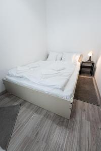 een wit bed in een kamer met een houten vloer bij King Seventeen Homes in Boedapest