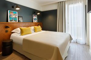 a bedroom with a large white bed with yellow pillows at RockyPop Grenoble Hotel in Grenoble