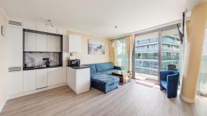 ein Wohnzimmer mit einem blauen Sofa und einer Küche in der Unterkunft Prywatne Apartamenty Sun & Snow w Wave z basenem in Misdroy