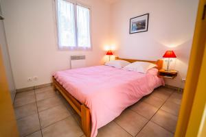 a bedroom with a large bed with a pink comforter at Les Chalets de la Vallee du Bes in Albaret-le-Comtal
