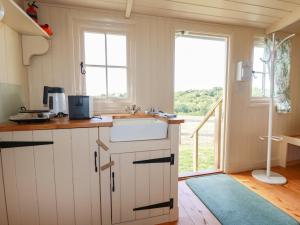 a kitchen with white cabinets and a sink and a window at Westering Sun in Bude