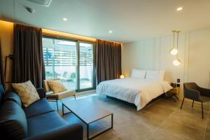 ein Hotelzimmer mit einem Bett und einem Sofa in der Unterkunft Hotel Pico in Tongyeong