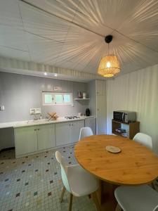 - une cuisine avec une table en bois et des chaises blanches dans l'établissement Entre rivière & bambous / Vue rivière / Parc arboré, à Saint-Juéry