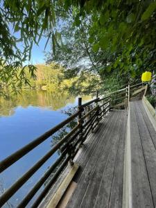 une promenade en bois à côté d'une étendue d'eau dans l'établissement Entre rivière & bambous / Vue rivière / Parc arboré, à Saint-Juéry