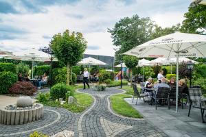 a patio with people sitting at tables and umbrellas at Landhotel Hopster in Rheine