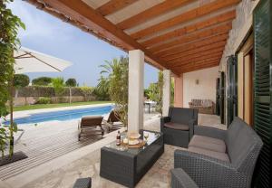 un patio con sillas, una mesa y una piscina en Ubac Pollença, en Sa Pobla