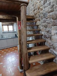 een houten wenteltrap in een keuken met een stenen muur bij Buscando el Norte in Cabrillanes
