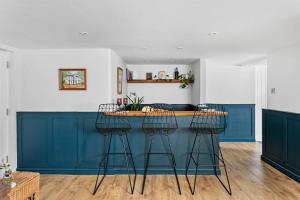 uma cozinha com um bar azul com três bancos em Coombe Bank - Seaboard spirit, contemporary chic with parking close to beach em Teignmouth