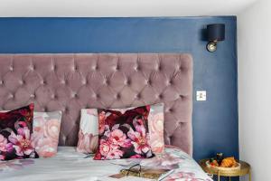 a bed with a pink headboard and pillows on it at Coombe Bank - Seaboard spirit, contemporary chic with parking close to beach in Teignmouth
