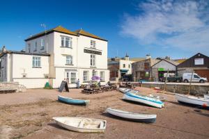 a group of boats sitting on the sand in front of a building at Coombe Bank - Seaboard spirit, contemporary chic with parking close to beach in Teignmouth