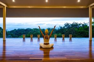 Eine Frau, die in einer Yoga-Position auf einer Etage sitzt. in der Unterkunft Aves Hotel Montezuma in Montezuma