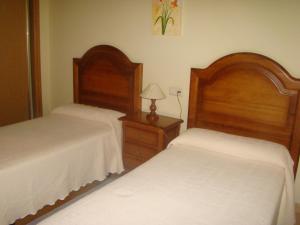 a bedroom with two beds and a dresser with a lamp at Apartamentos Peña Mar in Castropol