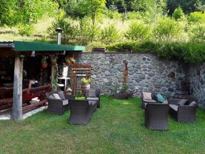 a yard with chairs and a stone wall at Seosko domacinstvo Imanje Medojevic in Mojkovac