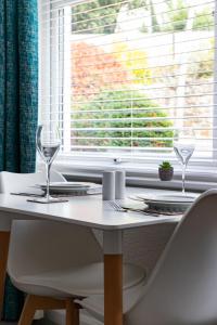 a white table with two wine glasses on it at 2 Chatsworth Riverscape Apartments - Peaceful apartment in great location with free parking overlooking the Gannel just a short walk from Newquays incredible beaches and local amenities in Newquay