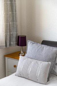 a bed with a pillow and a table with a lamp at 2 Chatsworth Riverscape Apartments - Peaceful apartment in great location with free parking overlooking the Gannel just a short walk from Newquays incredible beaches and local amenities in Newquay