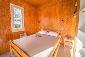 a bedroom with a bed in a wooden wall at Les Chalets de la Truyère in Le Malzieu-Ville