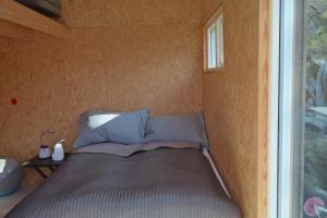a bed in a small room with a window at Keybutler Holiday Cabin Nettholmen in Kristiansand