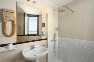 a white bathroom with a sink and a shower at Hotel Alda Pasaje in Gijón
