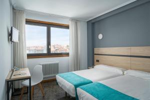 a hotel room with a bed and a desk and a window at Hotel Alda Pasaje in Gijón