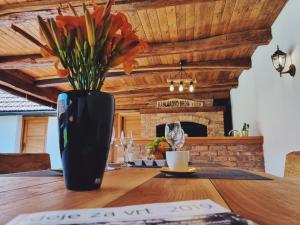 a black vase with flowers on a wooden table at Ruralna kuća za odmor Kablarovo Brdo in Krnjak