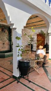 a man sitting in a chair on a patio with a potted plant at Riad Catalina in Marrakech