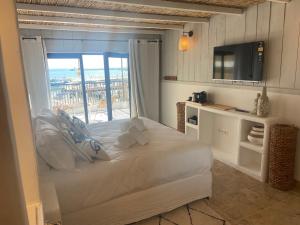 Schlafzimmer mit einem großen weißen Bett und einem Fenster in der Unterkunft Les Vagues in Saintes-Maries-de-la-Mer