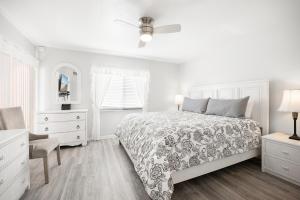 a white bedroom with a bed and a chair at Ocean Village Club J24 in Saint Augustine