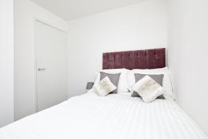 a white bed with four pillows on it at Modern 2 Bed House by City Centre in Nottingham