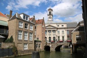 a building with a clock tower and a bridge over a river at B&B verDRAAId fijn in Dordrecht