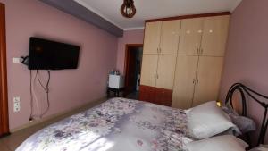 a bedroom with a bed and a flat screen tv at IOANNIS - Room with balcony near Limnopula in Gavrolímni