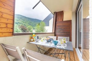 a table and chairs on a balcony with a large window at Le Patou in Saint-Lary-Soulan