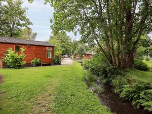 a log cabin with a yard and a tree at Tiggywinkle Beck Lodge in Windermere