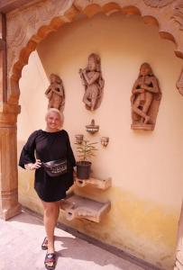 een vrouw die voor een muur met beelden staat bij Rigmor haveli in Jodhpur