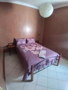 a bedroom with a bed with a purple comforter at Families Apartment in Martil