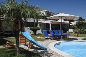 una piscina con scivolo, sedie e una palma di Sesimbra Stylish Villa by Homing a Sesimbra