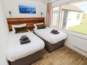 two beds in a room with a window at Chalfonts Cottage in Haverfordwest