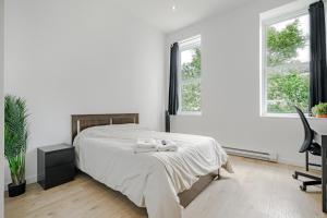 een slaapkamer met een bed, een bureau en 2 ramen bij HoMa Homestay Hostal by Olympic Stadium! in Montreal