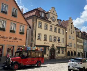 an old red trolley car parked in front of buildings at Hotel Eisenhut in Rothenburg ob der Tauber