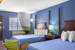 Cette chambre bleue comprend 2 lits et une chaise. dans l'établissement Rodeway Inn near Ft Huachuca, à Sierra Vista